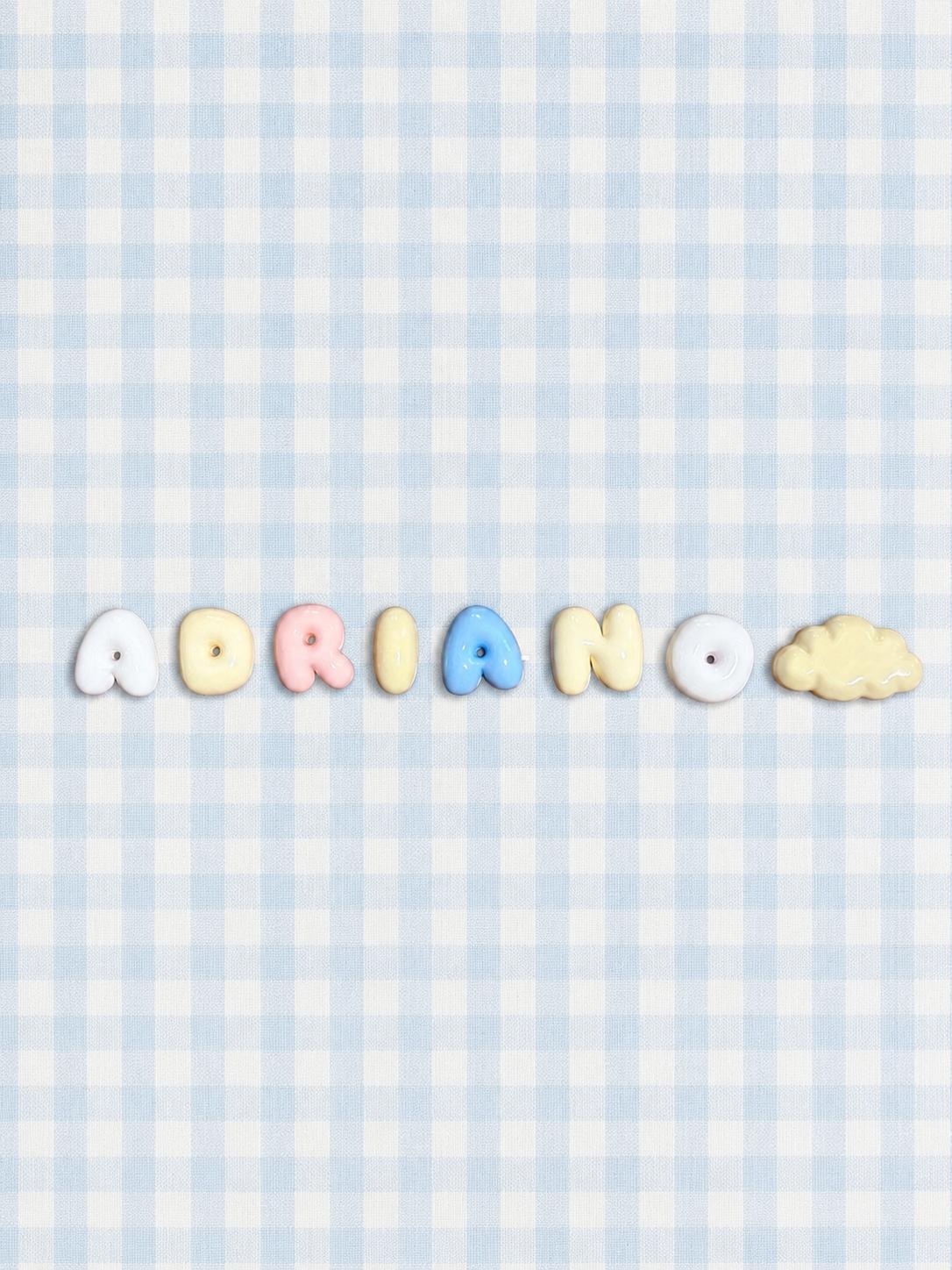 Nombre Adriano en letras bubble en tonos suaves con una nube, sobre un mantel de cuadros azul