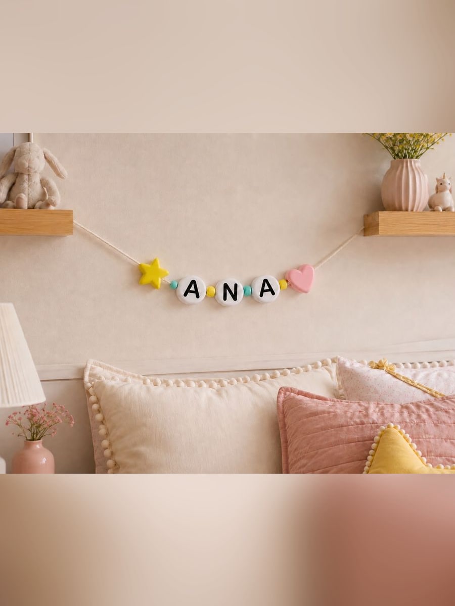 Guirnalda XL con el nombre Ana colgada en la pared sobre la cama, con una estrella amarilla y un corazón rosa enhebrados en la cuerda