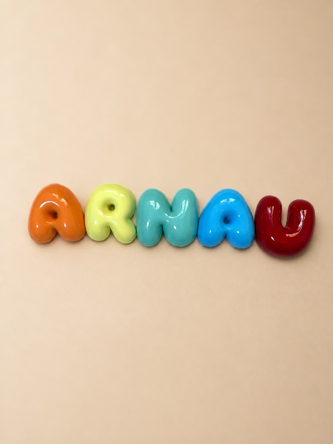 Nombre Arnau en letras bubble salmón, amarillo suave, menta, azul cielo y granate