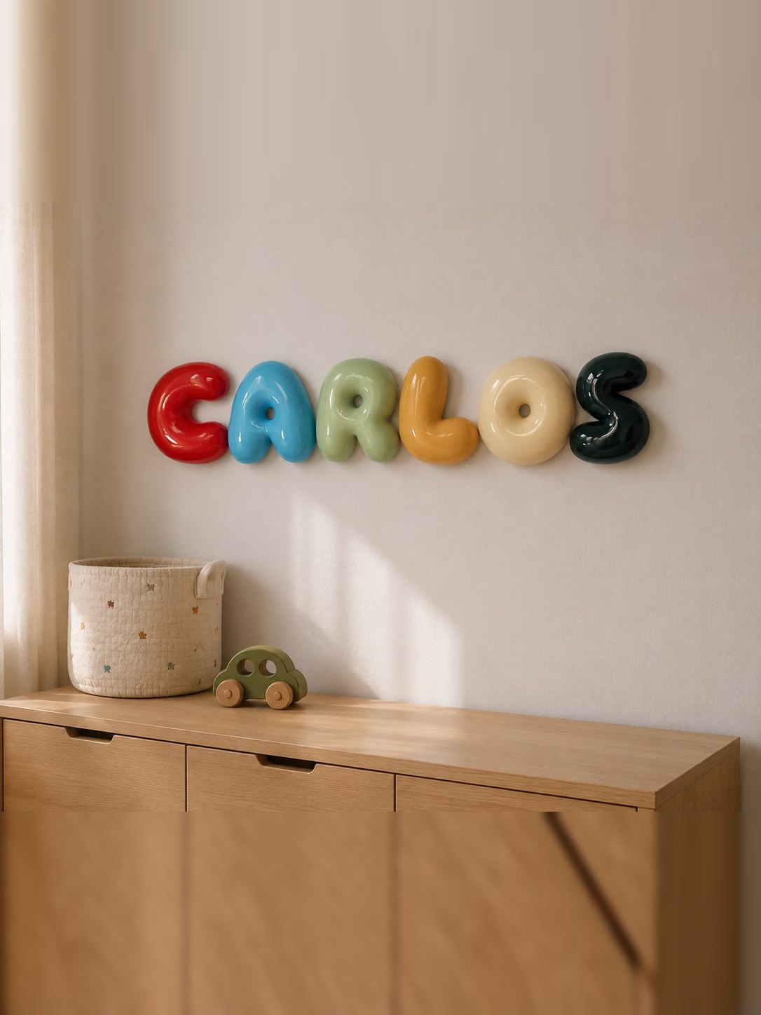 Nombre Carlos en letras bubble de 20 cm en granate, azul cielo, verde bebé, amarillo arena, albaricoque y verde botella sobre la cómoda