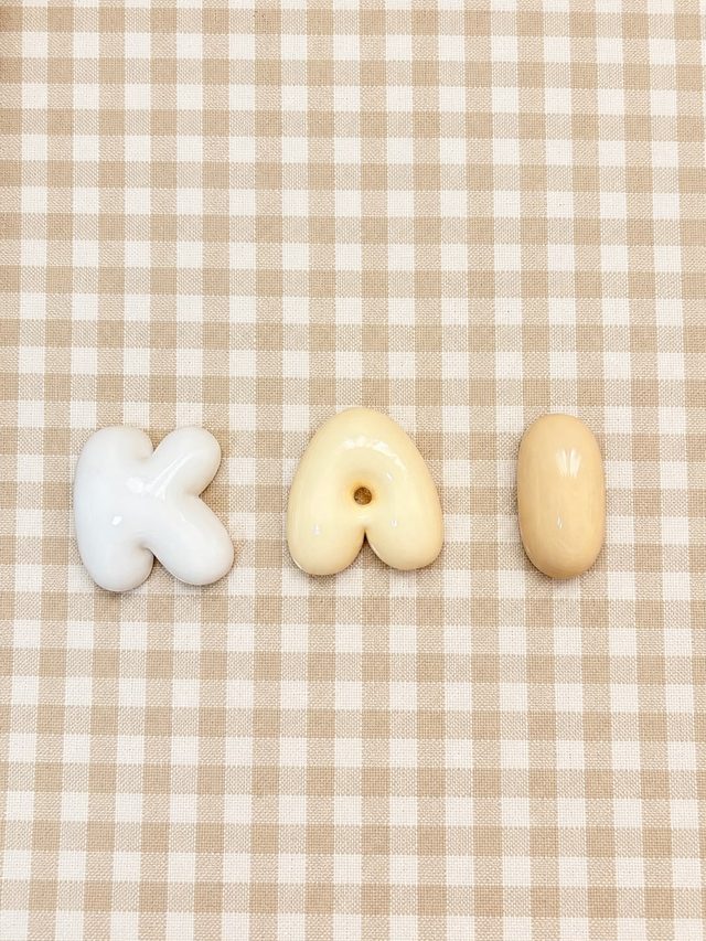 Nombre Kai en letras bubble en tonos blanco y vainilla sobre un mantel de cuadros beige