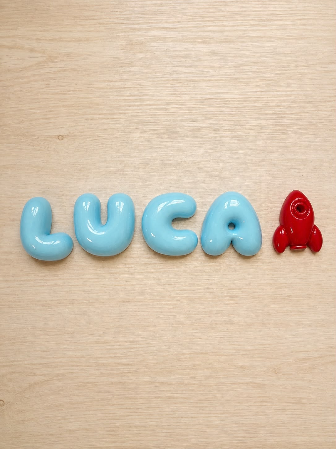 Nombre Luca en letras bubble azul pálido con un cohete granate
