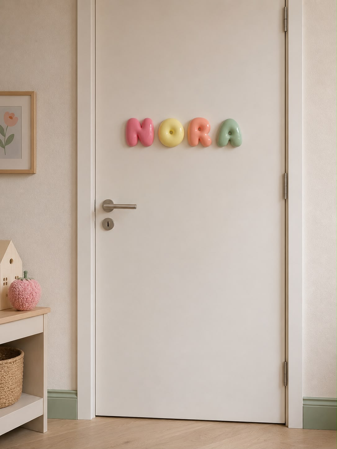 Nombre Nora en letras bubble rosa, natilla, melocotón y verde en su puerta