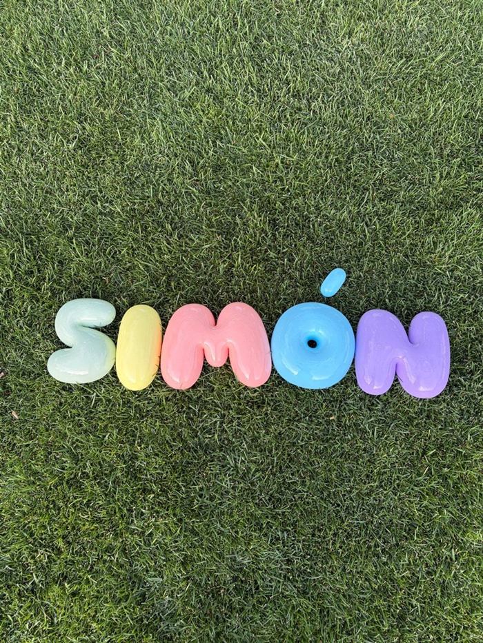 Nombre Simón en letras bubble pastel de 20 cm sobre el césped